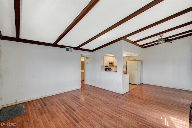 unfurnished living room with visible vents, vaulted ceiling with beams, baseboards, wood finished floors, and a ceiling fan