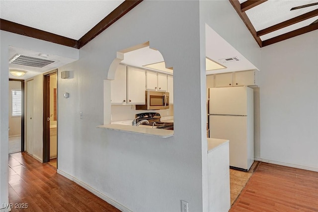 kitchen with visible vents, stainless steel microwave, freestanding refrigerator, light countertops, and range