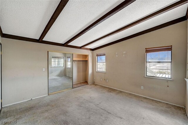 unfurnished bedroom featuring lofted ceiling with beams, a textured ceiling, and carpet flooring