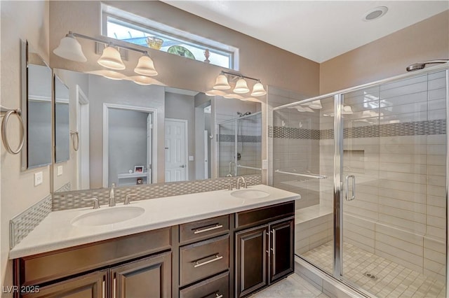 bathroom with a sink, a stall shower, and double vanity