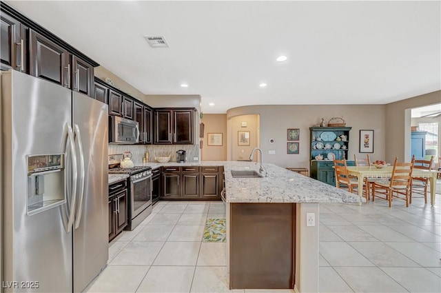 kitchen featuring visible vents, light tile patterned floors, decorative backsplash, appliances with stainless steel finishes, and a sink