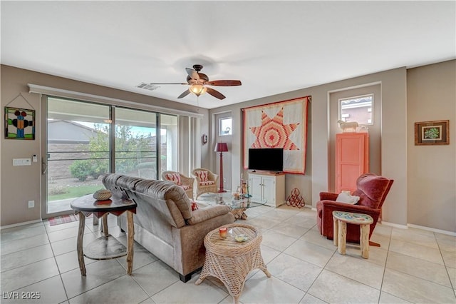 living room with light tile patterned floors, visible vents, baseboards, and a ceiling fan