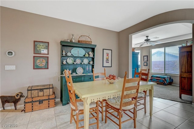 dining area featuring light tile patterned floors, a ceiling fan, and arched walkways