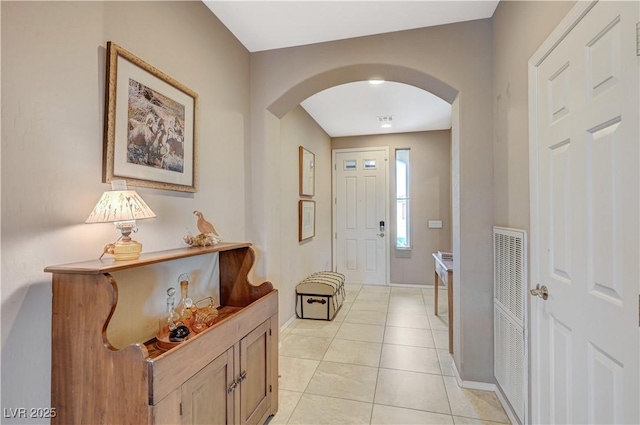 foyer with baseboards, arched walkways, and light tile patterned flooring