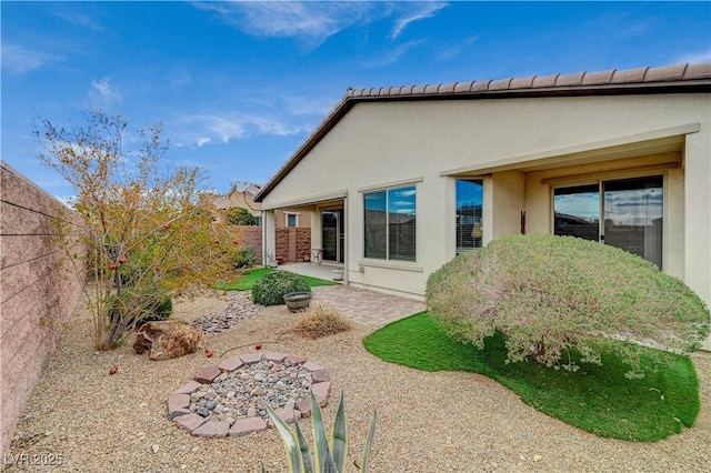 rear view of house with stucco siding, a patio, and a fenced backyard