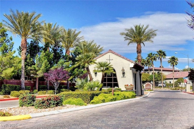 exterior space featuring curbs, street lights, a gated entry, and a gate