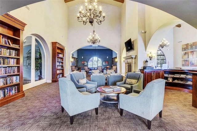 sitting room featuring a chandelier, carpet flooring, arched walkways, and built in shelves