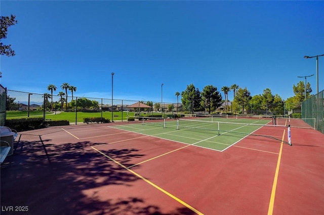 view of tennis court with community basketball court and fence