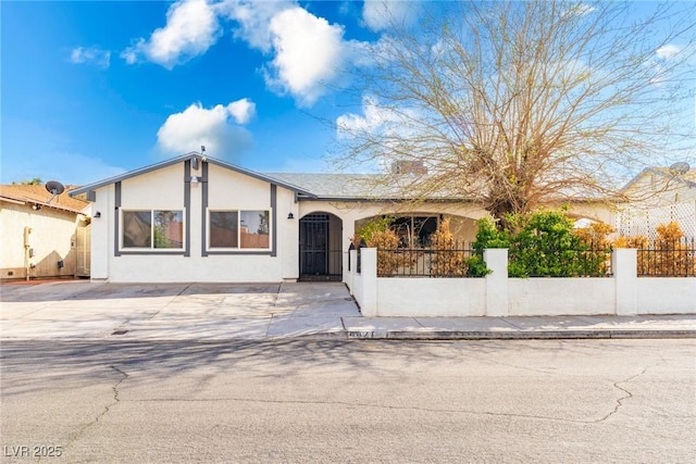 ranch-style home featuring a fenced front yard and stucco siding