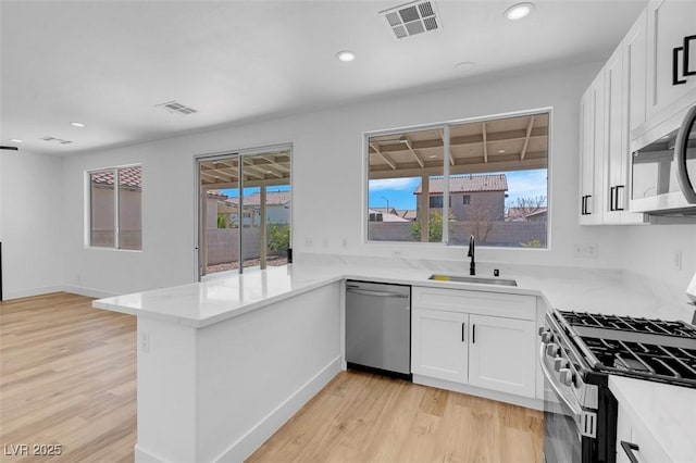 kitchen featuring a peninsula, visible vents, appliances with stainless steel finishes, and a sink