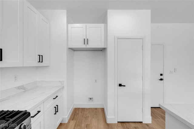 clothes washing area with light wood-type flooring and baseboards