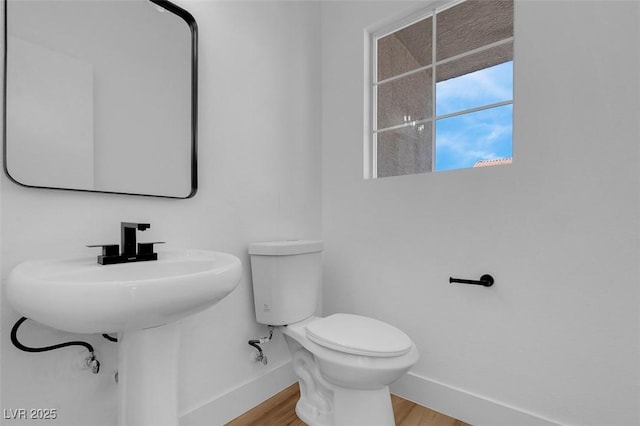 bathroom with baseboards, toilet, and wood finished floors