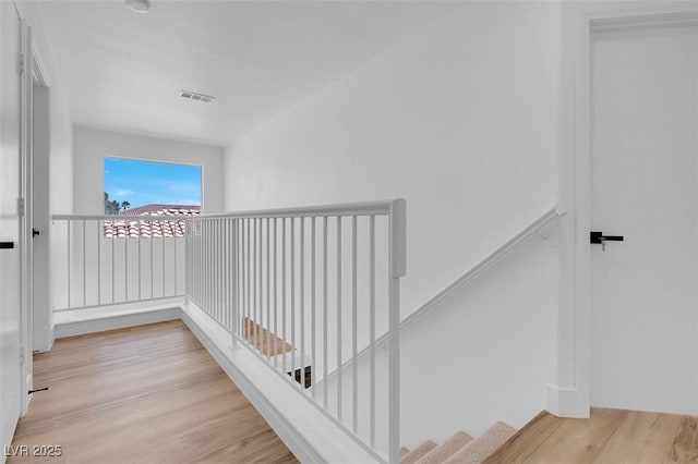 hallway featuring an upstairs landing, wood finished floors, and visible vents