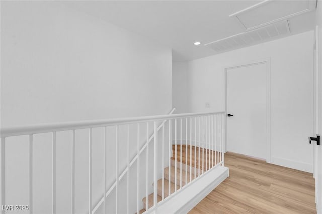 hall with attic access, recessed lighting, and light wood-style floors