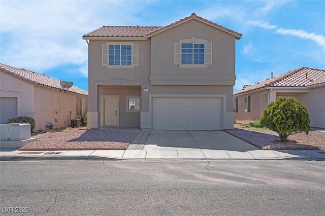 view of front of home with stucco siding, driveway, a tile roof, and a garage