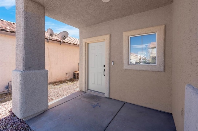 doorway to property with a tile roof, a patio area, and stucco siding