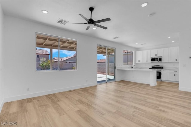 unfurnished living room featuring recessed lighting, light wood-style floors, visible vents, and a sink