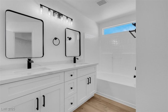 full bathroom featuring double vanity, visible vents, wood finished floors, and a sink