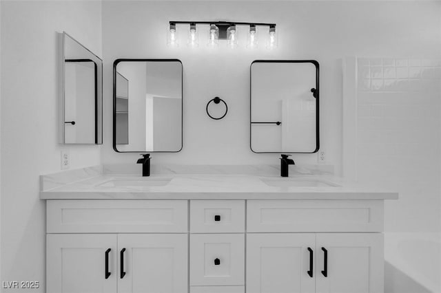 full bathroom featuring double vanity, a washtub, and a sink