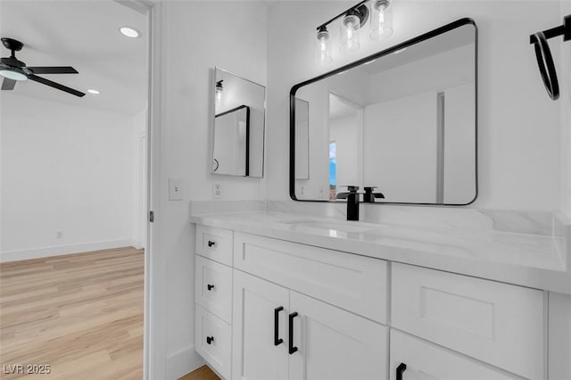 bathroom with baseboards, ceiling fan, recessed lighting, wood finished floors, and vanity