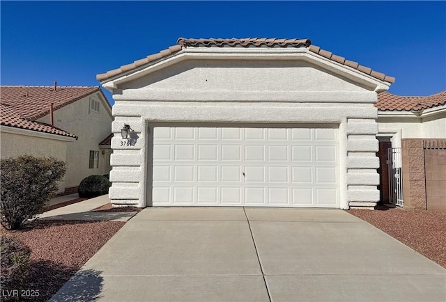 view of front of property with stucco siding, concrete driveway, a tile roof, and an attached garage