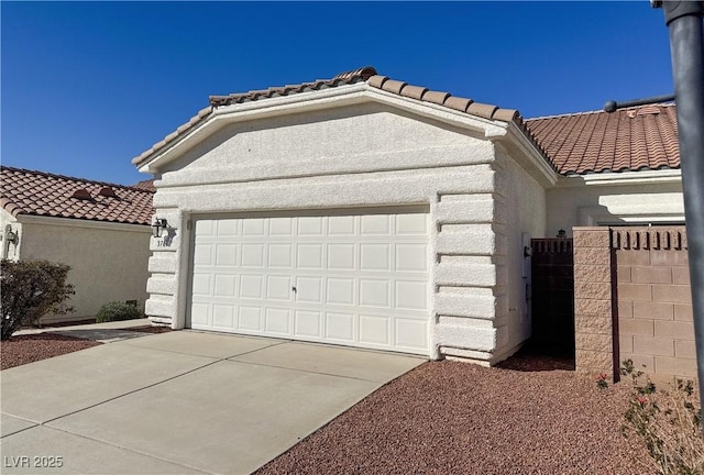 garage featuring concrete driveway and fence