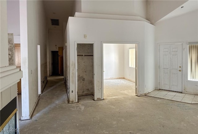 foyer entrance with visible vents and a towering ceiling