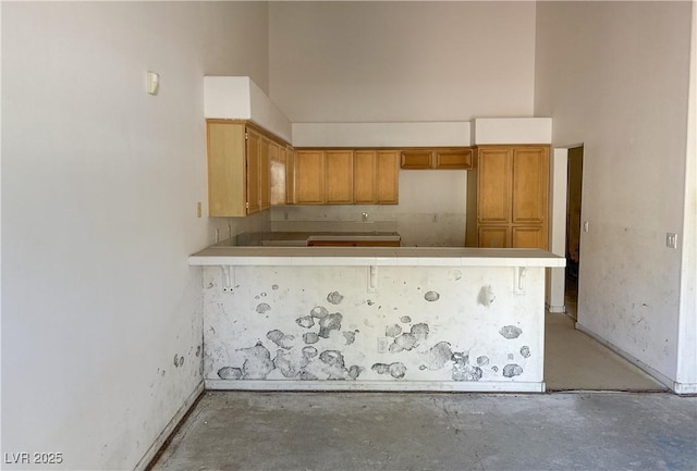 kitchen with brown cabinets, a peninsula, and unfinished concrete flooring