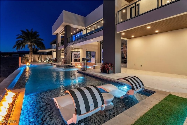 pool at twilight with an outdoor pool and a patio