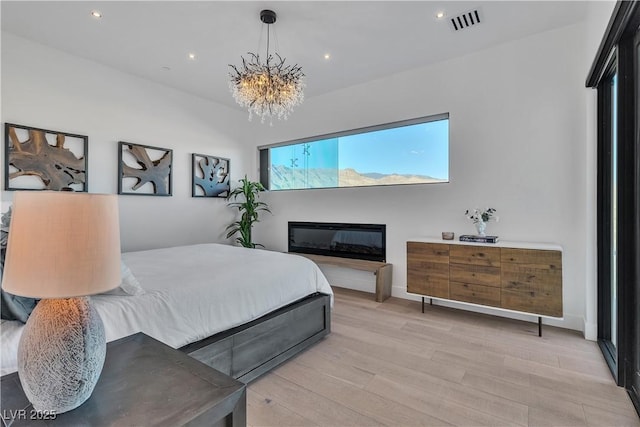 bedroom with light wood finished floors, visible vents, recessed lighting, and a chandelier