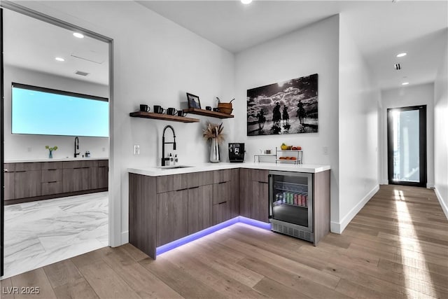 bar featuring baseboards, beverage cooler, light wood-type flooring, recessed lighting, and a sink