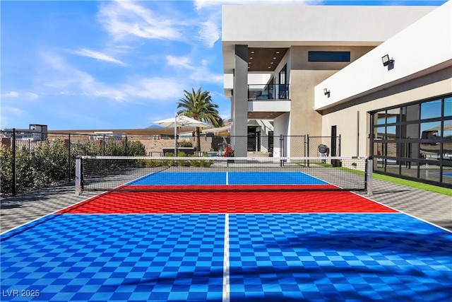 view of basketball court with a tennis court and fence