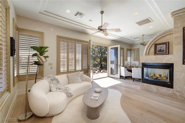 9801 Orient Express Ct, Las Vegas, NV 89145 - living room featuring a multi sided fireplace, ceiling fan, visible vents, and wood finished floors
