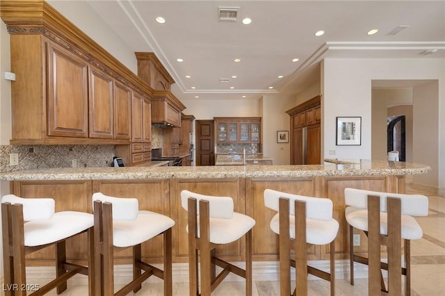9801 Orient Express Ct, Las Vegas, NV 89145 - kitchen featuring brown cabinetry, visible vents, stove, light stone counters, and a peninsula