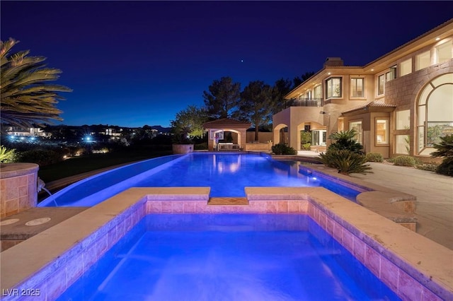 9801 Orient Express Ct, Las Vegas, NV 89145 - pool at night with a pool with connected hot tub and a patio area