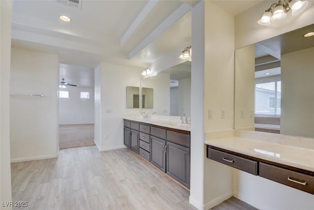 full bathroom with a sink, wood finished floors, double vanity, baseboards, and ceiling fan