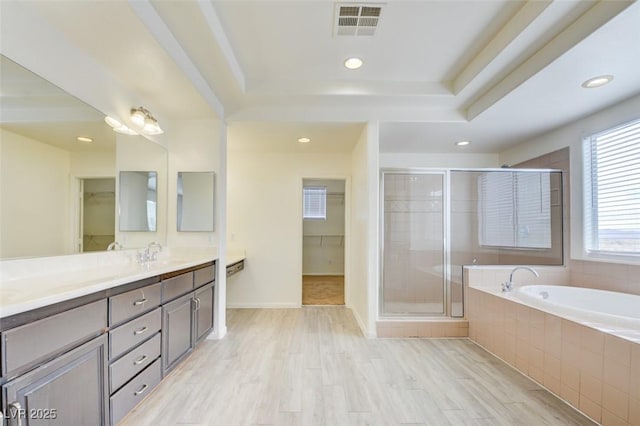 bathroom featuring visible vents, wood finished floors, a shower stall, a bath, and vanity