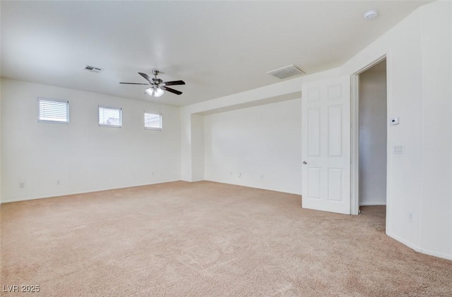 carpeted spare room with visible vents and a ceiling fan