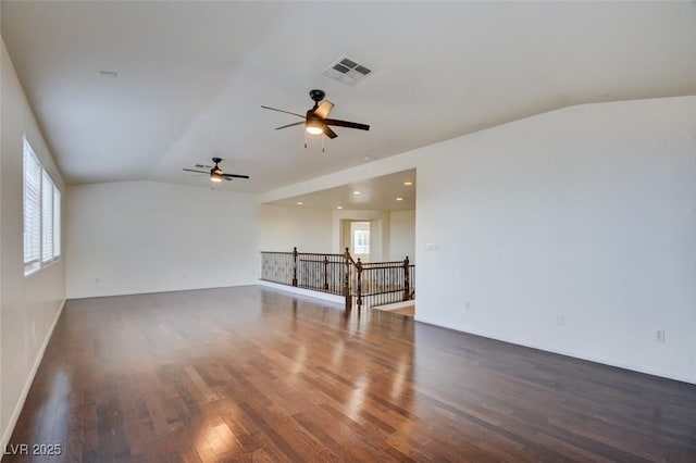 empty room featuring vaulted ceiling, wood finished floors, visible vents, and ceiling fan