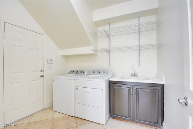 washroom featuring a sink, cabinet space, washing machine and dryer, and light tile patterned floors