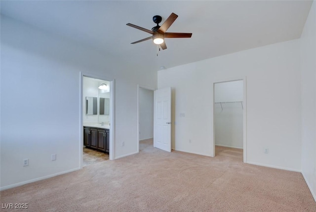 unfurnished bedroom with a walk in closet, light carpet, a closet, and ensuite bath