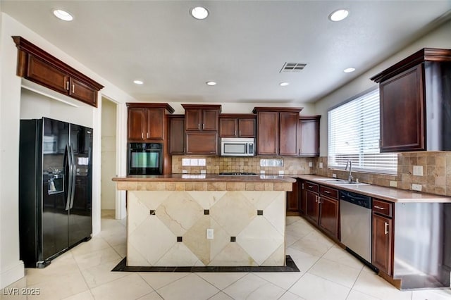 kitchen with visible vents, a kitchen island, a sink, black appliances, and light countertops