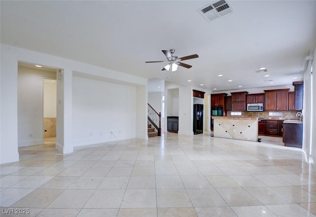 unfurnished living room with visible vents, ceiling fan, stairway, light tile patterned floors, and a sink