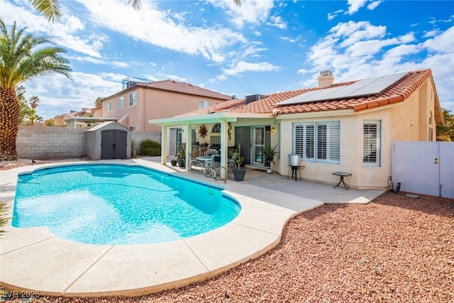 view of pool with a patio, an outdoor structure, a fenced backyard, and a shed