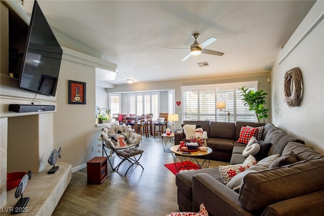 living room with visible vents, baseboards, wood finished floors, and a ceiling fan