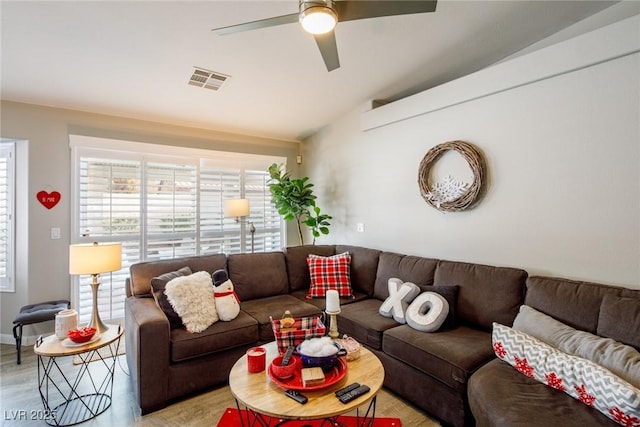 living room with visible vents, light wood-style flooring, and ceiling fan