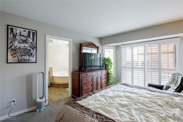 carpeted bedroom featuring connected bathroom and baseboards