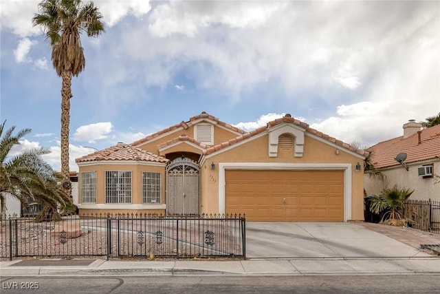 mediterranean / spanish-style home featuring stucco siding, a fenced front yard, concrete driveway, an attached garage, and a tiled roof