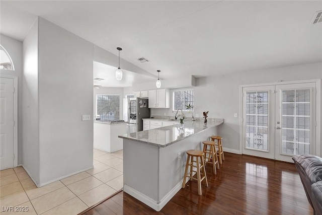 kitchen with a sink, white cabinetry, freestanding refrigerator, a peninsula, and a breakfast bar area