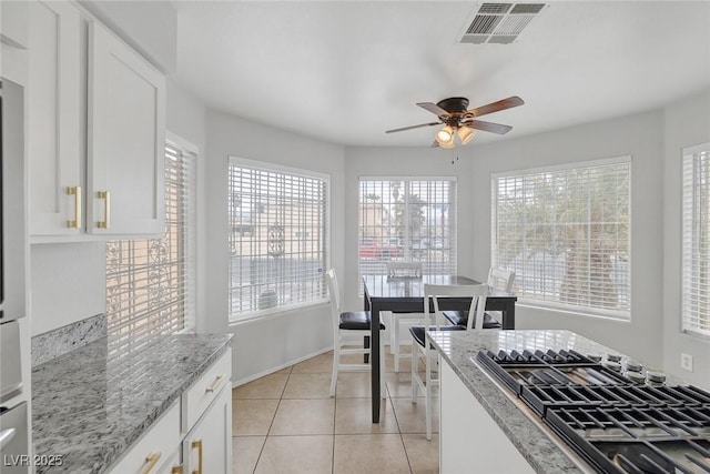 kitchen featuring light stone countertops, visible vents, a ceiling fan, light tile patterned flooring, and white cabinetry